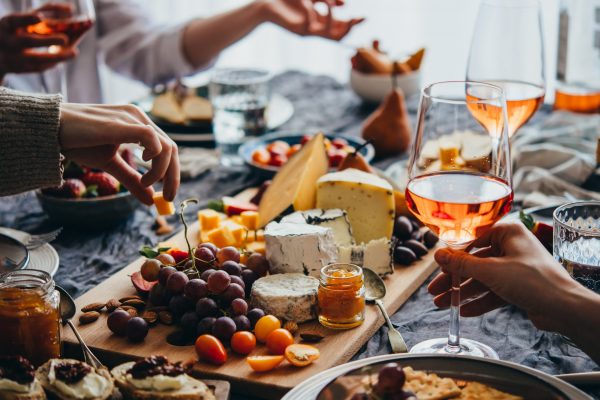Friends having a dinner party with different kinds of appetizers and rose wine.